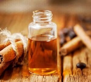 A bottle of cinnamon oil sitting on top of a wooden table.