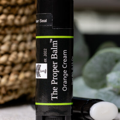 Lip balm labeled "The Proper Balm" Orange Cream.