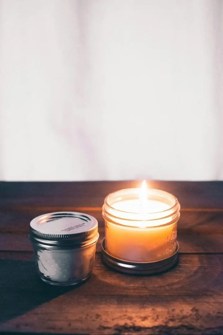 A candle is lit next to a tin container.