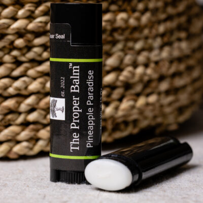 Lip balm labeled Pineapple Paradise, woven background.